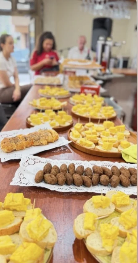 Barra larga llena de pinchos de tortilla, croquetas y empanada