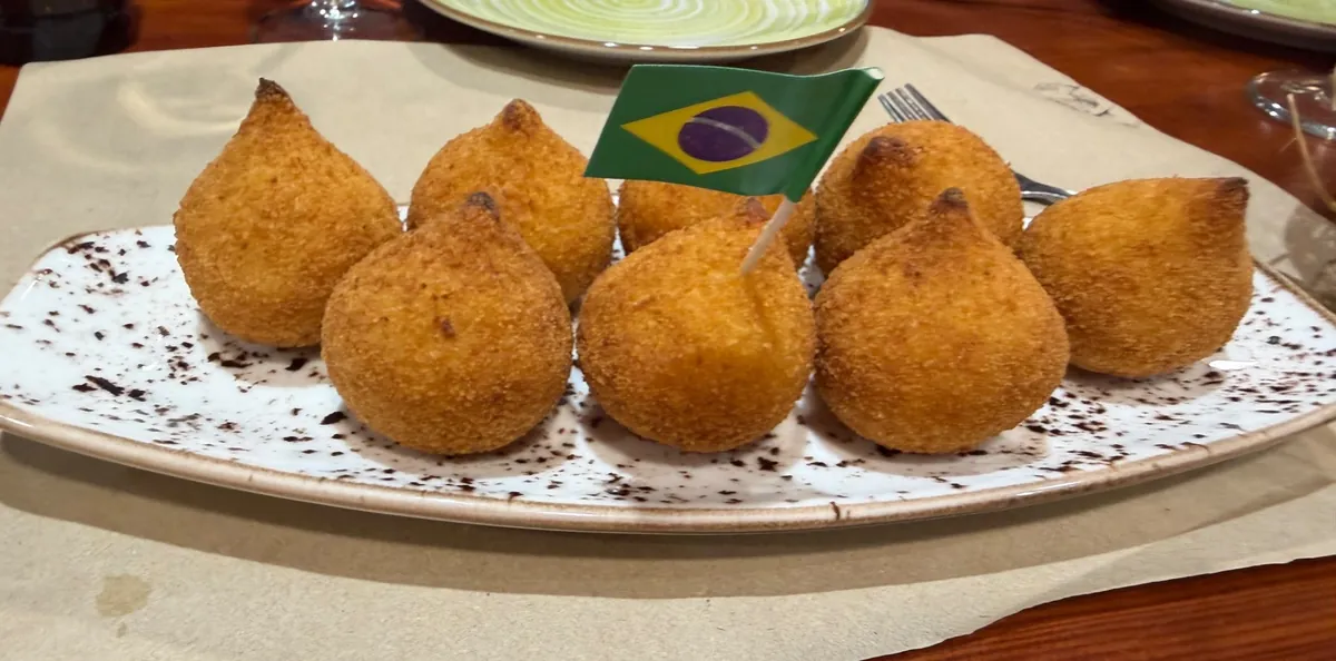 Plato de coxinhas doradas con banderita de Brasil en Manas