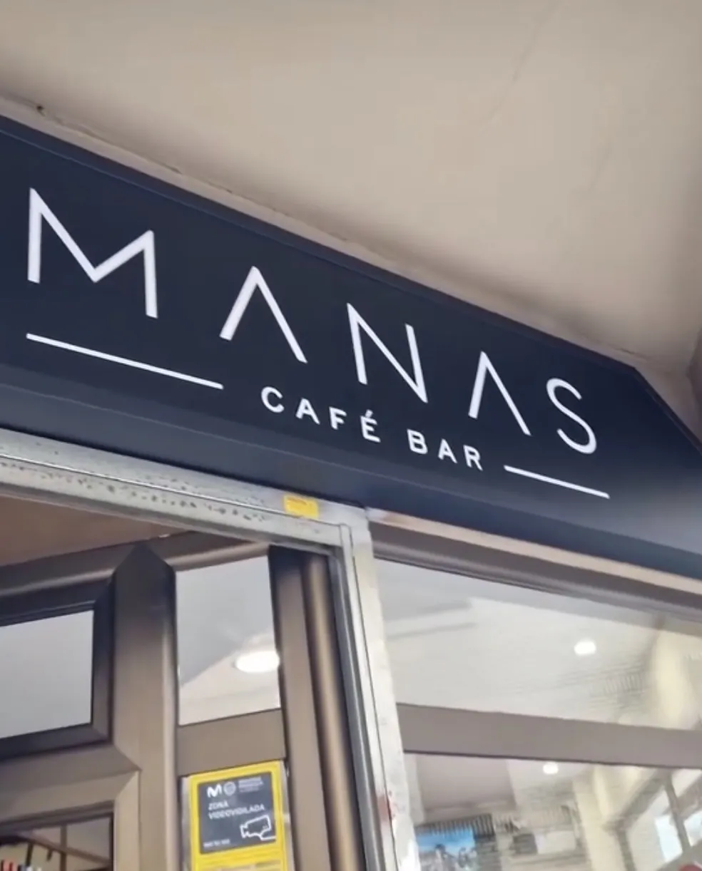 Rótulo negro de Manas Café Bar sobre la entrada del local